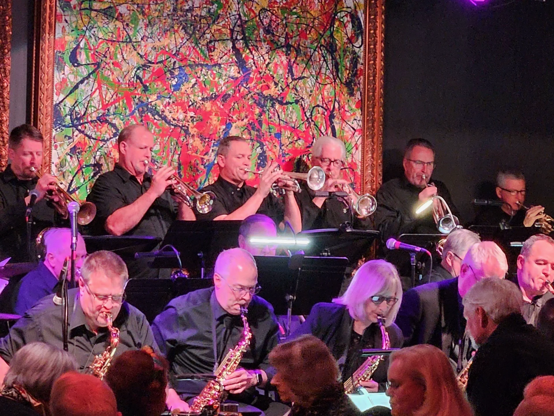 JoySwing trumpet section performing beneath a colorful abstract mural